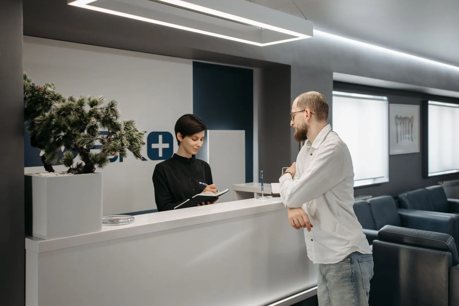A receptionist noting an appointment for a patient at a modern clinic reception desk