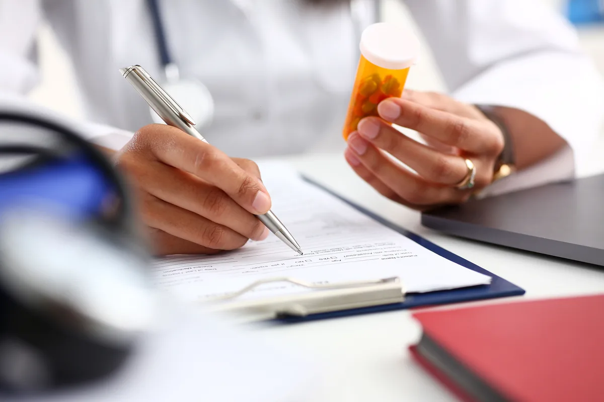 A doctor handing a printed prescription to a patient